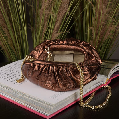 Small roundish brown metallic clutch with a gold metal strap that can be added to wear as a cross-over bag.
